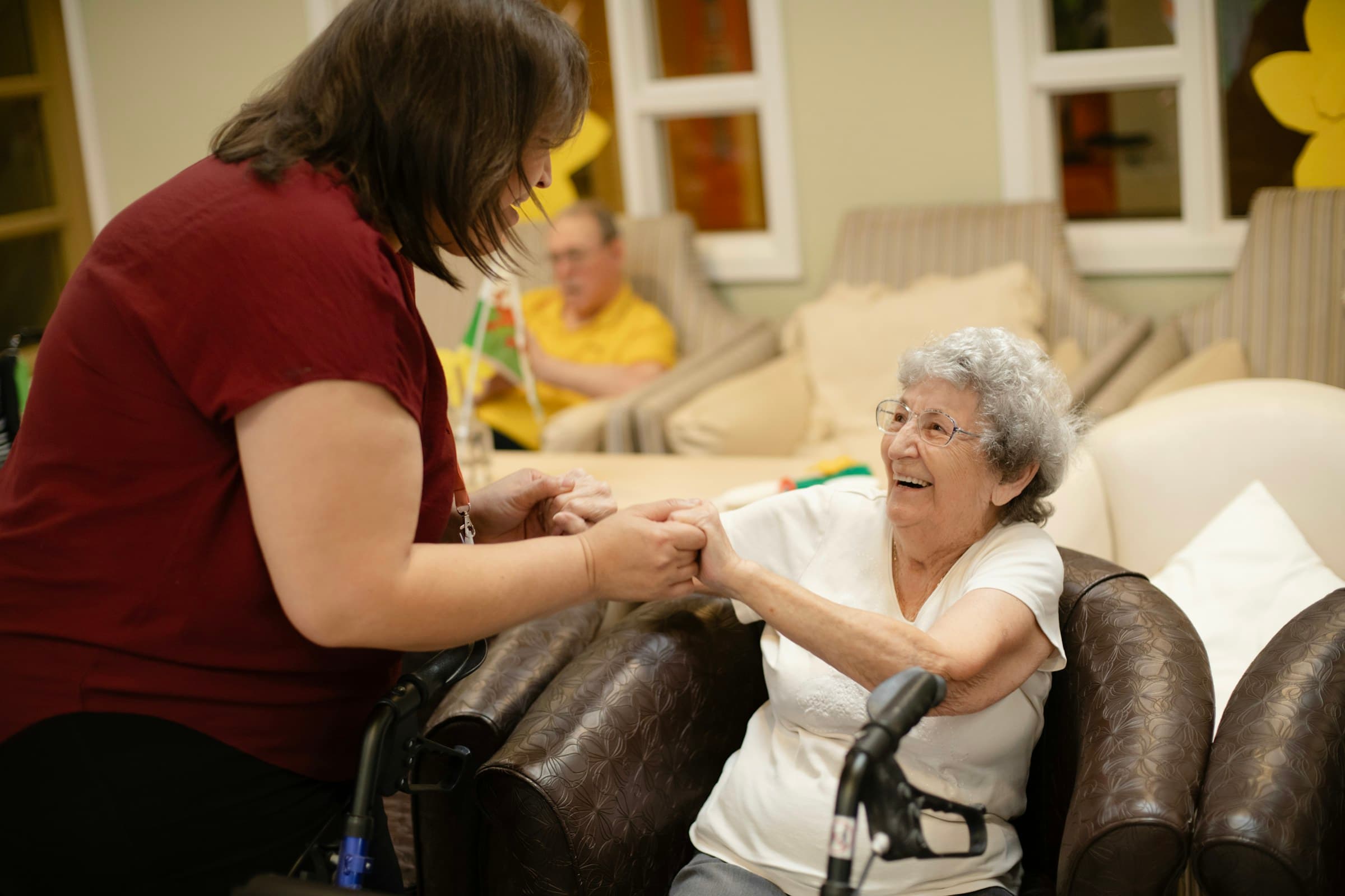 A caregiver laughing with an older woman as she stands with her walker